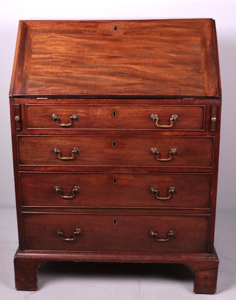 George III Mahogany Slant Top Desk: Mahogany, with drop front revealing cubbies and drawers, over two full drawers and a double drawer with drop pulls and bracket feet. Circa early 19th C. Dimensions: 41.5 x 30 x 19.5 in. NOTE: Wear con