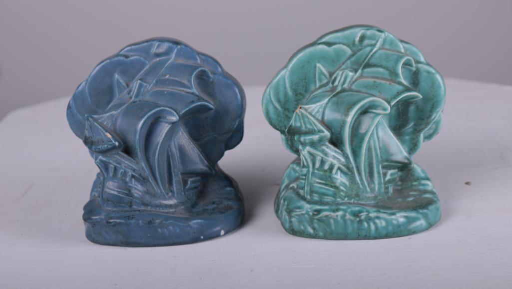 Rookwood Pottery Bookends: Each marked on base #2695, one in blue, one in green, ship at sea design. Green marked 1927, blue marked 1937... both marked with "X".Dimensions: 6 x 5 x 3 in.NOTE: Both with chip to ship, bot