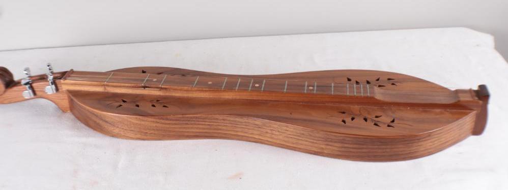 Kentucky Artisan Dulcimer: with scroll headstock, Signed "Rodney Hensley, Jackson Co. Kentucky #97, in walnut with bellflower carving and cutouts. Dimensions: 36 x 8.5 x 3 in. NOTE: Good shape