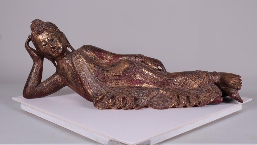 Carved Figurine of A Reclining Buddha: Carved wooden reclining buddha, with red lacquer and gold finish. Dimensions: 11 x 31 x 8 in.NOTE: Good