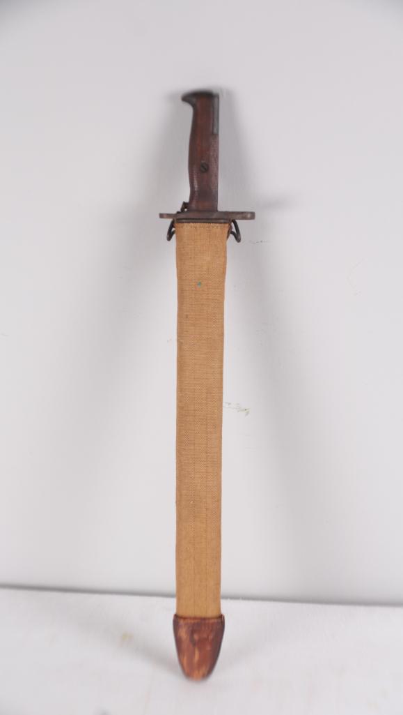 US SA 1909 Bayonet with scabbard: 16 in. blade with wood handle, 17 in. Canvas scabbard with leather tip. Serial number 424181. Locking mechanism works with scabbard. Dimensions: 22 x 3.5 x 2 in. NOTE: Appears to be original patina