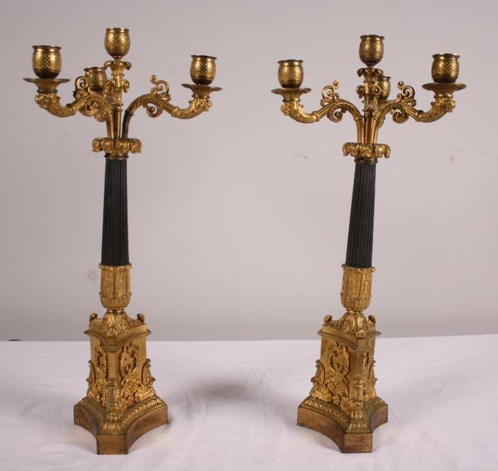 Pair of Parcel Gilt Four Light Candelabra: With a central light surrounded by three lights, over an ebonized column and raised on a classical plinth Dimensions: 22 x 9 x 9 in. NOTE: Wear consistent with age and use