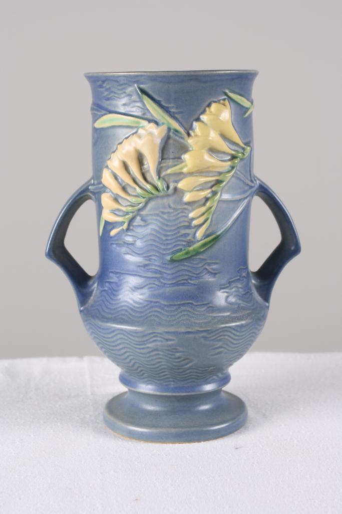 Roseville Pottery Freesia Handled Vase: Blue ground, marked on base. Dimensions: H 9.5 x W 7 x D 5 inches NOTE: No evidence of cracks, chips or repairs