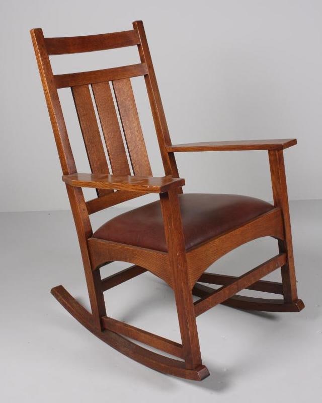 Harvey Ellis for Stickley Rocking Chair: With a straight crest rail over a three board splat, the leather upholstered seat flanked by shaped arms. The whole raised on four square legs supported by stretchers and rockers. Dimensions: H 41 x W
