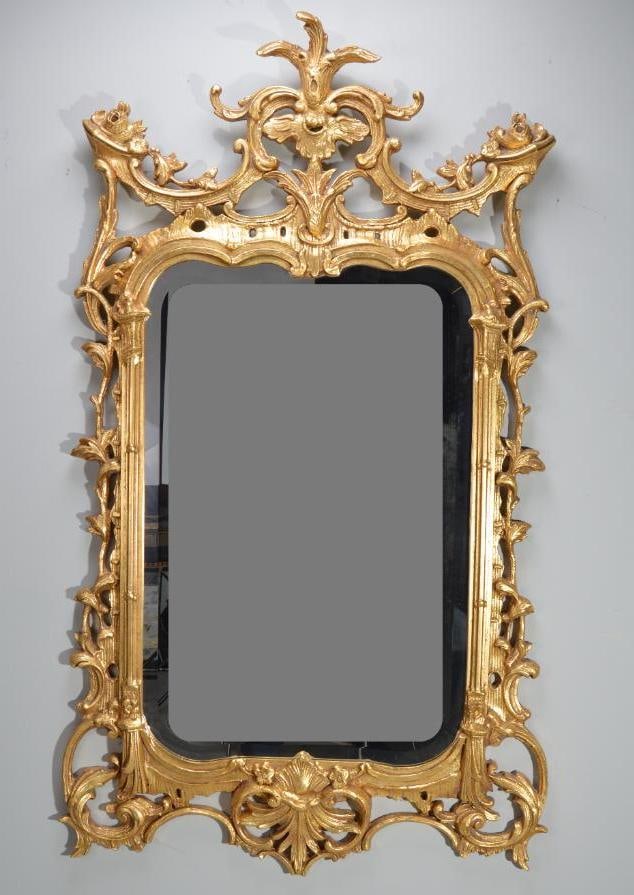 George III Style Giltwood Mirror: With a shaped beveled glass flanked by acanthus frame surmounted by a foliate finial Dimensions: H 54 x W 33 x D 1 inches NOTE: Wear consistent with age and use