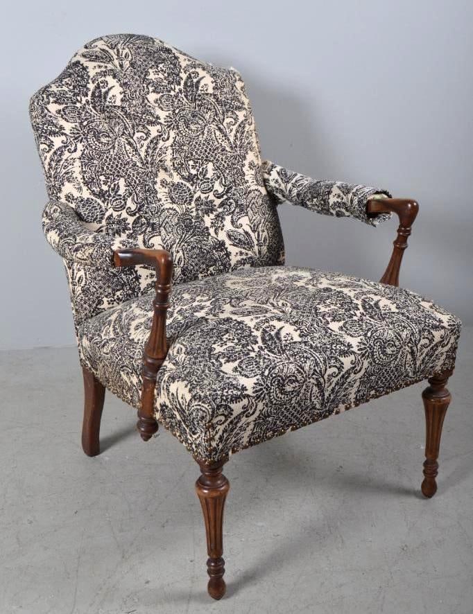 George III Style Upholstered Armchair: Walnut frame with fully upholstered body and shaped crest rail, upholstered arms, black & white floral fabric, and round tapered and fluted legs. Circa 1880. 36.5 x 27 x 32 in. Good condition. Wea
