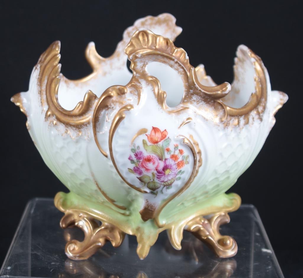 Sevres Handled Bowl: Gilt edge with acanthus handles and feet. Marked on bottom. Dimensions: H 6.5 x W 5 x D 4.5 inches NOTE: Wear consistent with age and use