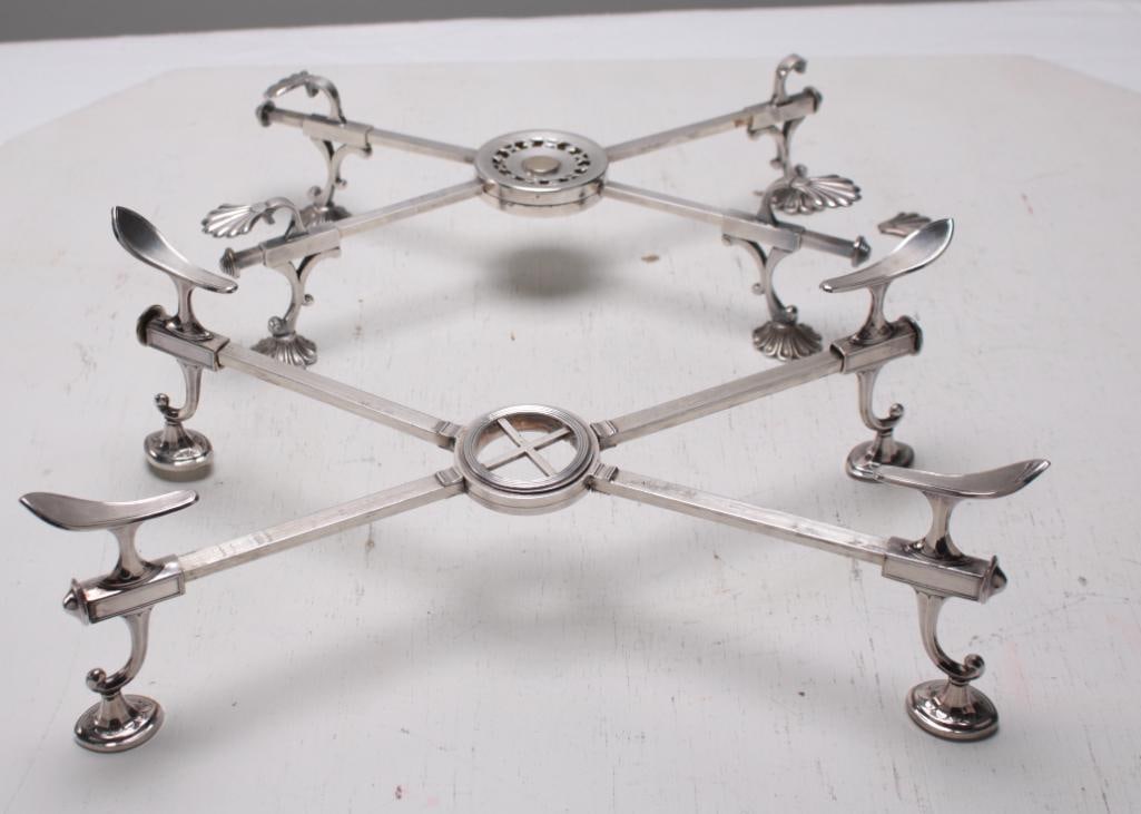 Two (2) Silverplate Trivets: One 19th Century with indecipherable marks, with scallop shell knees on lily pad feet, adjustable pads with compacting center. The Second unmarked with shaped knees on urn form feet, adjustable pads w