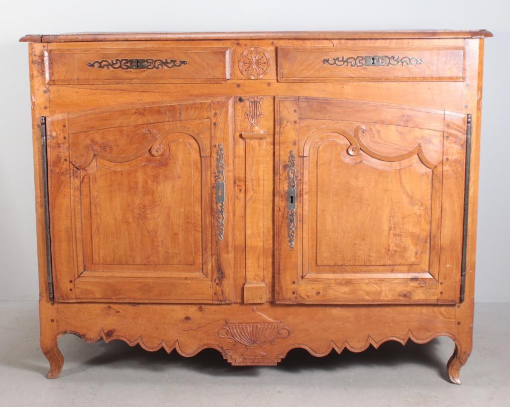 French Provincial Fruitwood Sideboard: With a moulded rectangular top over two carved drawers over two paneled and carved doors, the whole raised on four tapering square legs. Dimensions: H 41 x W 53 x D 24 inches NOTE: Wear consistent wit