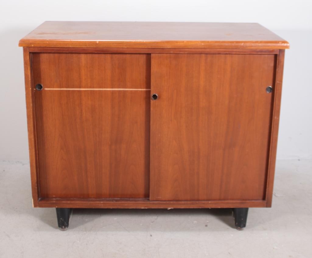 A Walnut Mid Century Console: With a rectangular top over two sliding doors, raised on a plinth Dimensions: H 29 x W 36 x D 18 inches NOTE: Significant scratching to top and left door