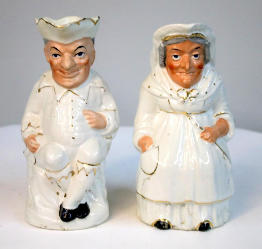 Pair of Punch and Judy Style Figural Character Jugs: Pair of porcelain figural character jugs modeled as seated male and female figures, likely representing Punch and Judy theatrical characters. The male figure wears a tricorn-style hat with exaggerated