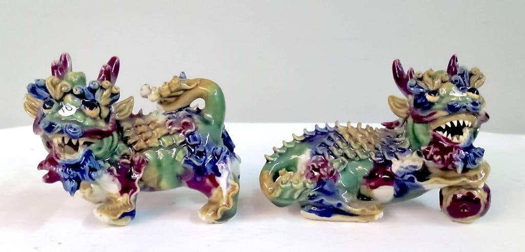 Pair of Chinese Glazed Porcelain Foo Dogs: Pair of Chinese porcelain guardian lion (foo dog) figures modeled in recumbent and standing poses, each with open mouth and stylized mane, decorated in a mottled sancai-style glaze of green, blue,