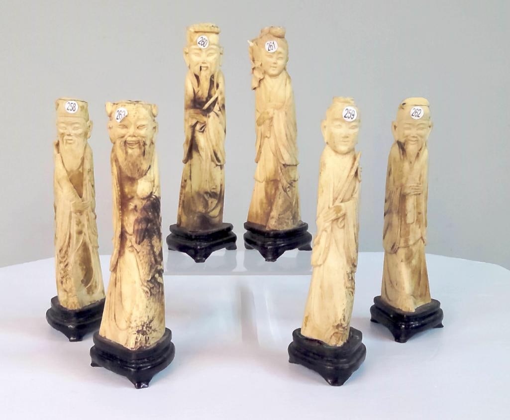 Six Carved Figures of Chinese Immortals: Group of six carved bone or bone-style figures depicting robed Chinese immortals or scholars, each standing in flowing garments and mounted on carved wood bases. The figures likely represent members o