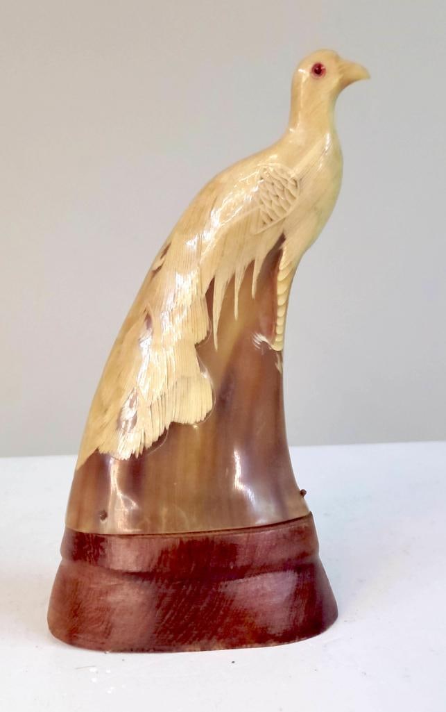 Carved Horn Bird Figure on Wooden Base: Carved horn figure of a bird in standing profile, with finely incised feather detailing and inset red glass eyes, mounted on a turned wood base; likely mid-20th century decorative carving. Dimensions: