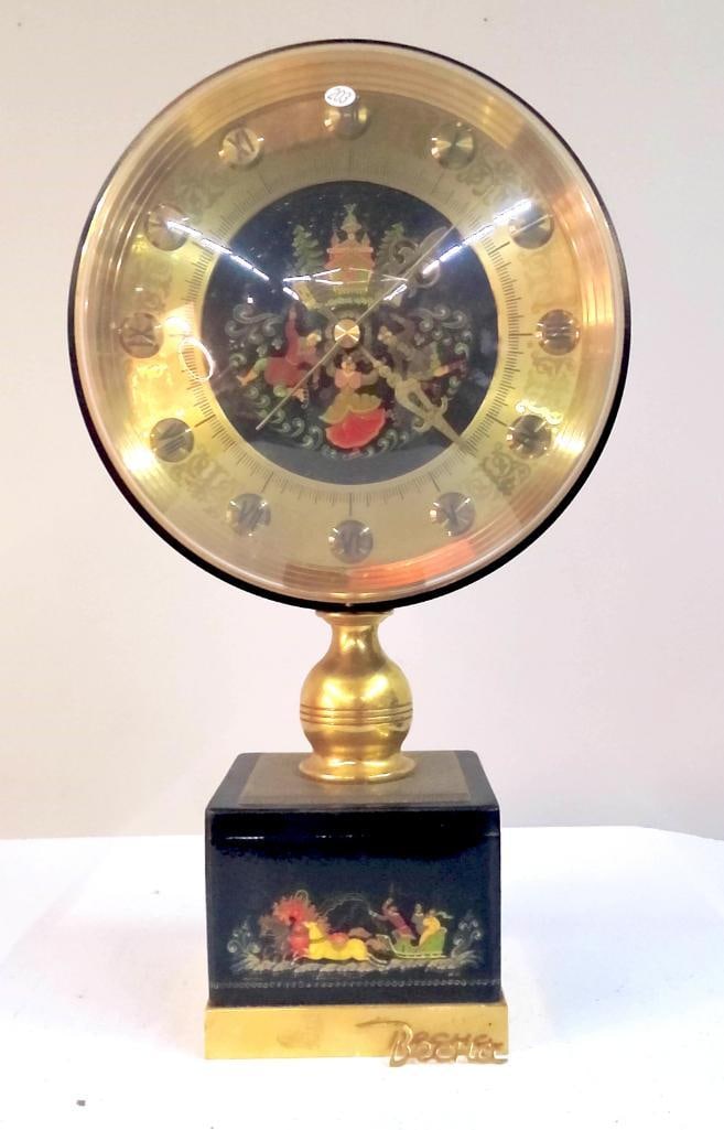 Becha Figural Musical Anniversary Clock with Dome: Mid-century novelty clock by Becha, featuring a brass-tone dial with applied Roman numeral hour markers and a central figural scene of dancers beneath a stylized pavilion. Mounted on a black
