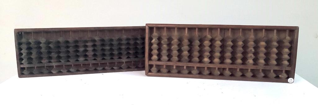 Two Wooden Abaci - Suanpan Type: A pair of rectangular wooden abaci of traditional Chinese form, each fitted with multiple vertical rods and carved wooden beads arranged in upper and lower decks. The frames are constructed of