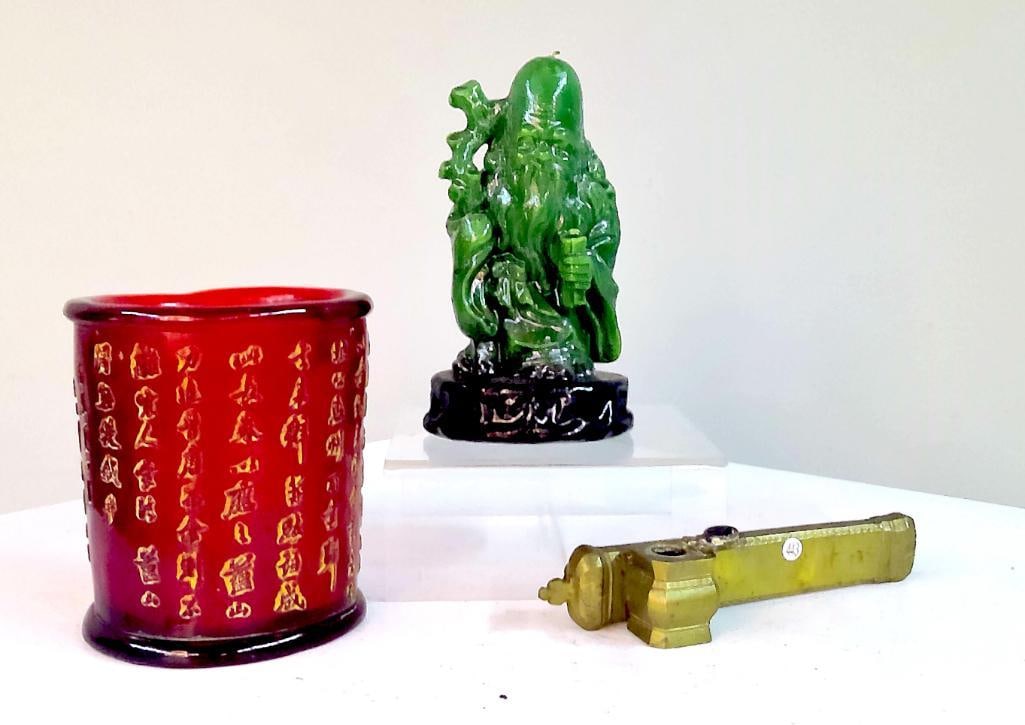 Group of Asian-Style Decorative Objects: Group comprising a red glass cylindrical candle holder with gilt-highlighted calligraphic decoration and interior candle, a green figural candle modeled as a longevity figure on integral base, and a