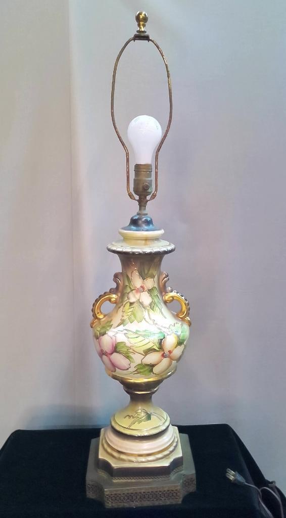 Hand-Painted Porcelain Table Lamp with Floral Decoration: A porcelain table lamp of urn form featuring hand-painted floral decoration in soft pinks, greens, and cream tones, with raised gilt accents outlining the design. The body is flanked by small scrolled