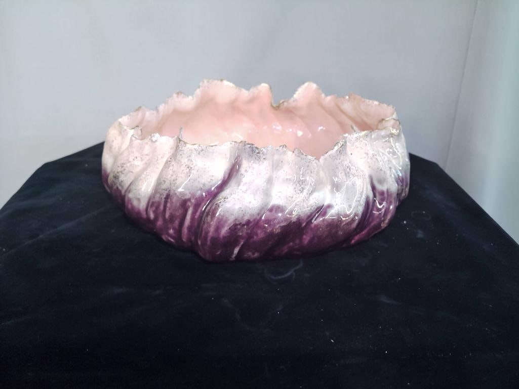 Majolica-Style Art Pottery Bowl, Purple Drip Glaze: Circular ceramic bowl with undulating rim, decorated in mottled purple and white glaze with pink interior, underside bearing an indistinct incised mark. Dimensions: H 5 x W 12 x D 12 inches NOTE: Surf