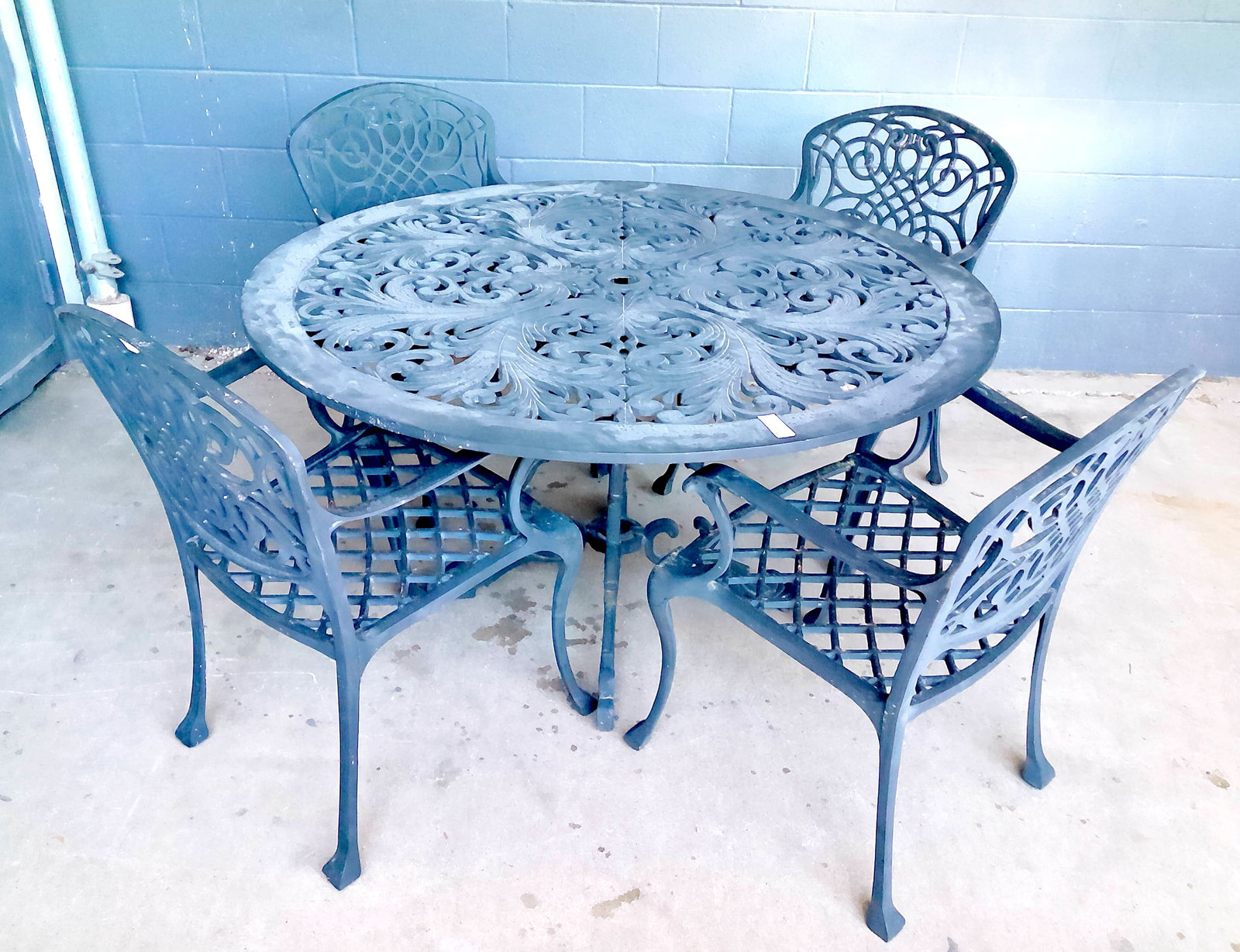 Five-Piece Cast Aluminum Patio Set: Decorative cast aluminum outdoor patio set comprising a round openwork table and four matching chairs. The table features an ornate scrolling foliate design with pierced top and conforming pedestal ba
