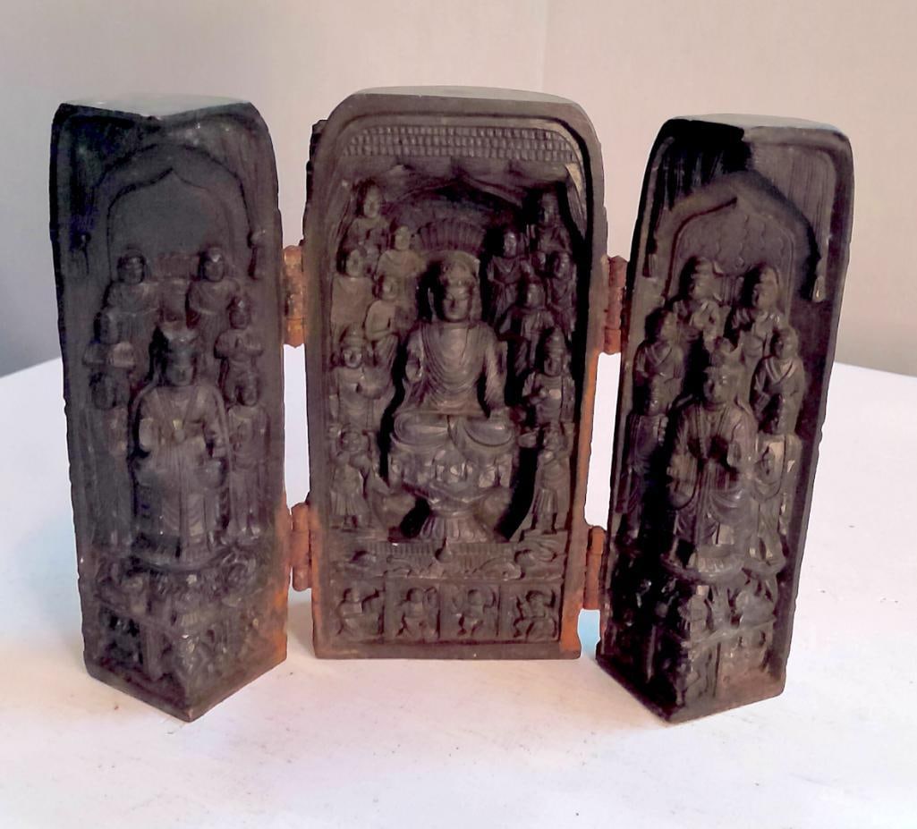 Chinese Carved Soapstone (or Soft Stone) Triptych Shrine: A hinged, three-panel devotional shrine carved in dark-toned stone, likely soapstone or a similar soft stone, featuring a central seated Buddha in relief surrounded by attendant figures within an arch
