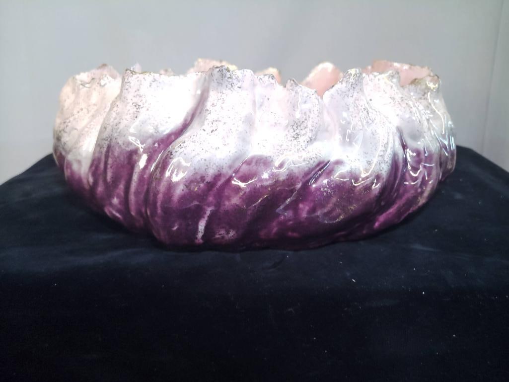 Majolica-Style Art Pottery Bowl, Purple Drip Glaze: Circular ceramic bowl with undulating rim, decorated in mottled purple and white glaze with pink interior, underside bearing an indistinct incised mark. Dimensions: H 5 x W 12 x D 12 inches NOTE: Surf