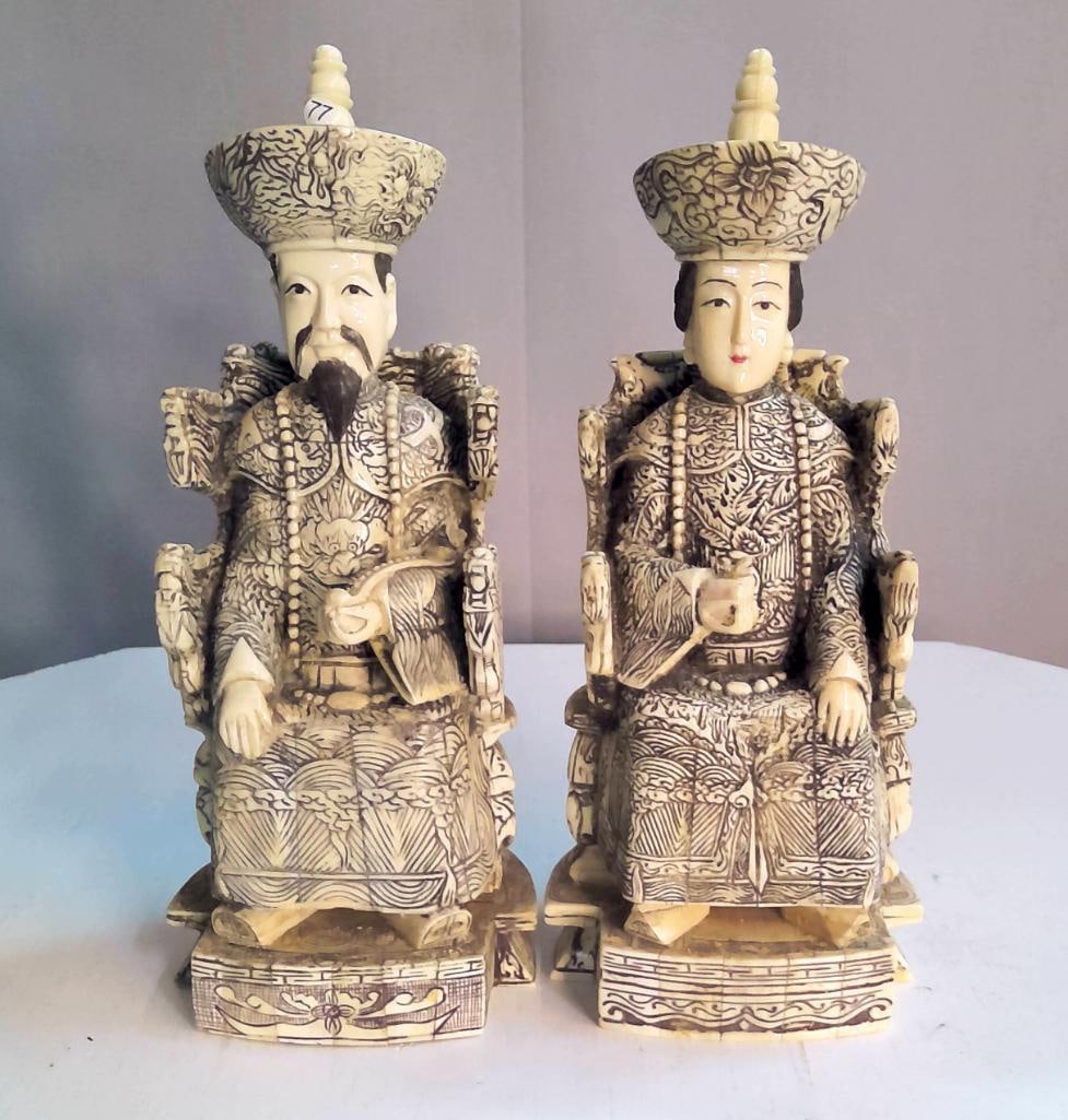 Pair of Carved Bone Seated Emperor and Empress Figures: Carved bone figural group depicting a seated emperor and empress in traditional robes, each rendered with dense incised decoration including dragons, clouds, and stylized wave motifs, both figures sea