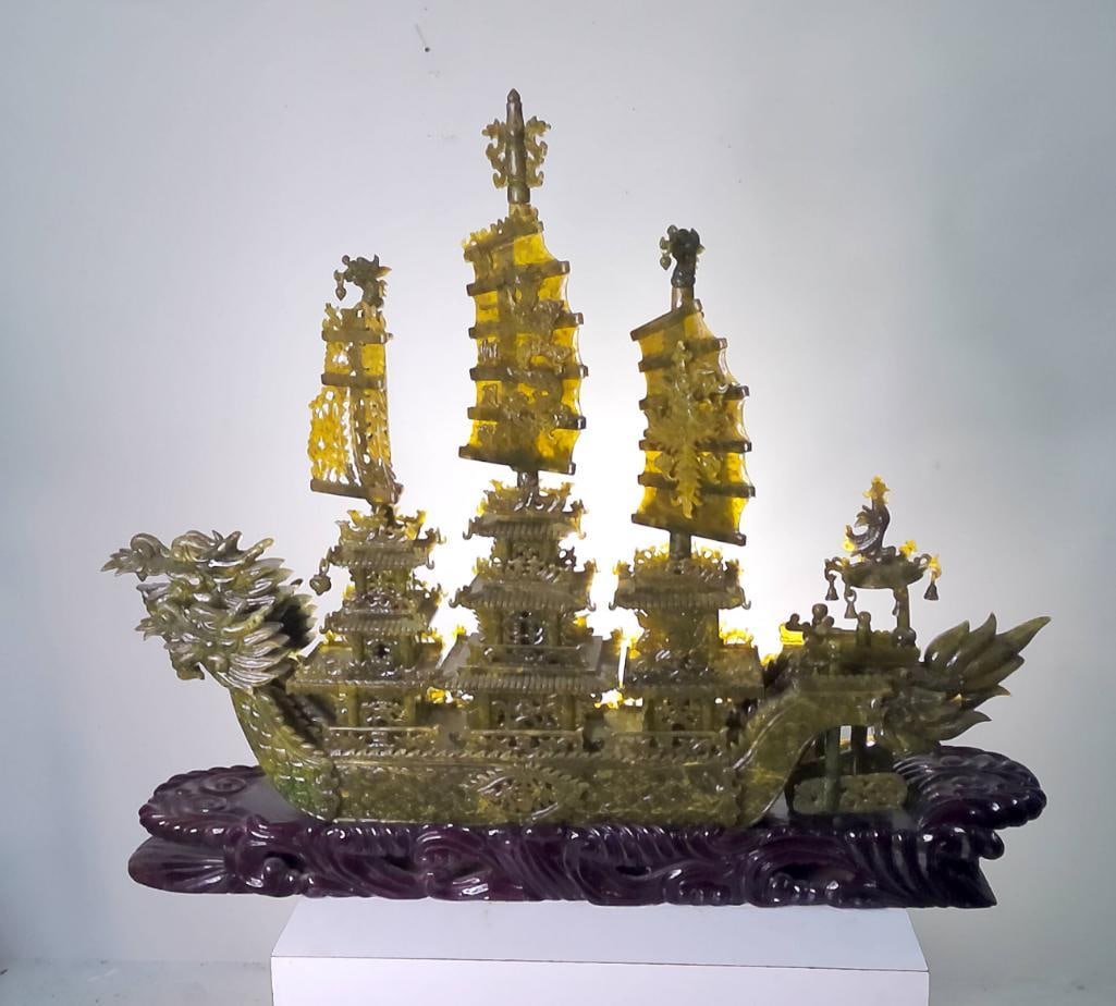 Large Chinese Carved Hardstone Dragon Ship on Hardwood Stand: Late 20th century. Finely carved translucent olive-green hardstone dragon ship, possibly Xiuyan jade or related serpentine material, modeled with dragon-form prow and stern, three masted sails, multi-
