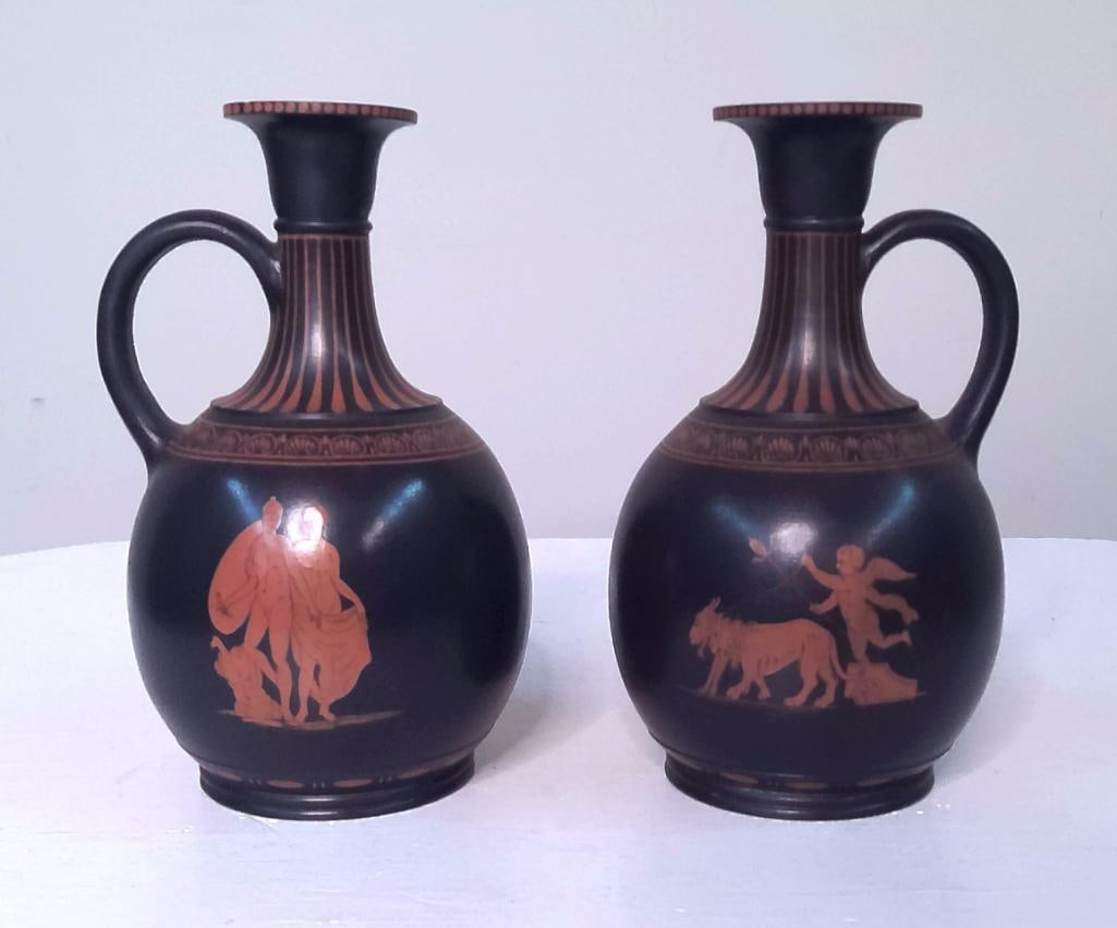 Pair of Wedgwood Black Basalt Encaustic-Decorated Classical Jugs: Each of baluster form with loop handle and terracotta-red encaustic decoration depicting classical figural scenes within ornamental borders, after ancient Greek vase painting traditions. No marks visi