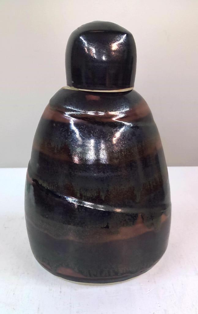Studio Pottery Covered Jar: Wheel-thrown stoneware covered jar with domed lid, finished in a mottled black, brown, and olive glaze over a bulbous form. The interior is finished with a contrasting white glaze and spiral decoratio
