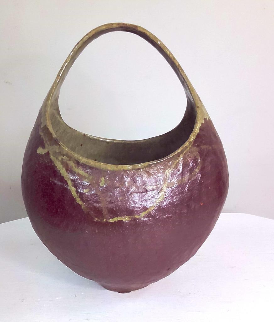 Michael Imes Basket-Form Studio Pottery Vessel: Hand-built stoneware basket-form vessel with arched handle and asymmetrical opening, decorated in mottled burgundy and olive glazes. Impressed "Imes" mark to underside. A sculptural vessel cha