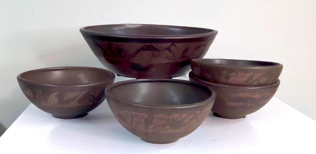 Five-Piece Studio Pottery Bowl Set: Comprising one large serving bowl and four matching individual bowls, each with matte brown glaze and abstract earth-tone decoration. Raised on three-point kiln feet. Dimensions: H 3.5 x W 13.5 x D 13