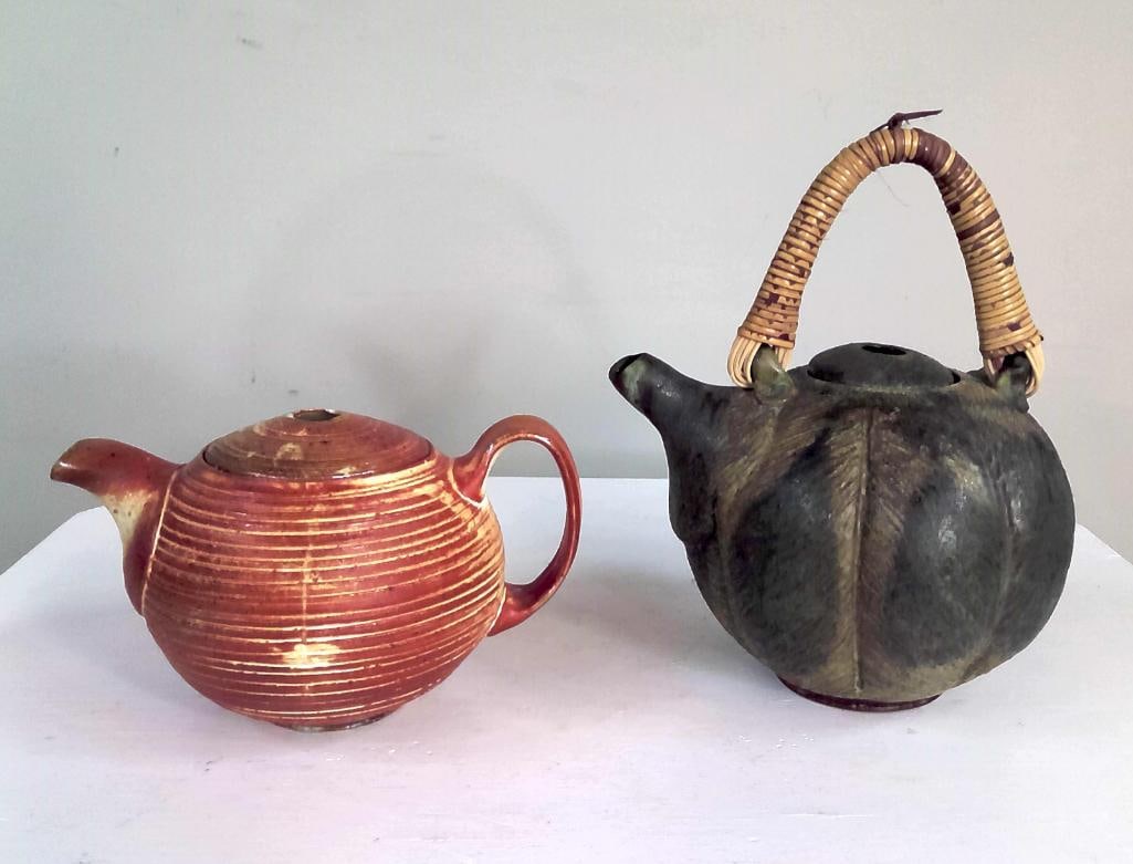Two Studio Pottery Teapots: Group comprising two hand-crafted stoneware teapots. The first of compressed globular form, decorated with concentric incised bands beneath a reddish-brown glaze and fitted with a matching cover. The 