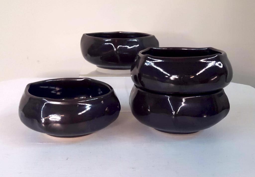Four Contemporary Studio Pottery Black Glazed Bowls: Group of four hand-thrown studio pottery bowls, each with glossy black glaze and faceted rim decoration. Similar forms and glaze treatment suggest production by a single studio potter. Unmarked aside 