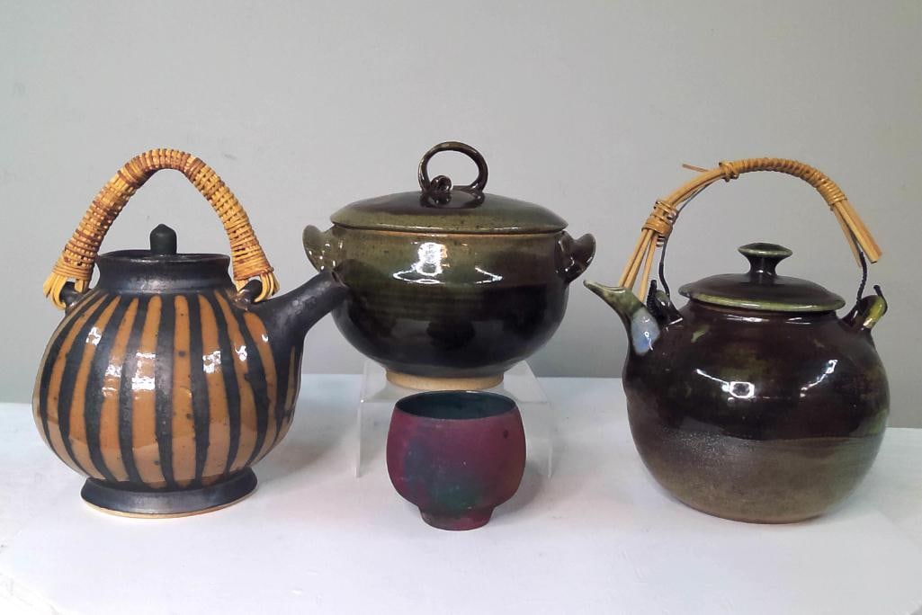 Four Studio Pottery Tea and Table Articles: Collection of four hand-thrown studio pottery articles comprising a striped teapot with woven rattan handle, a glazed teapot with swing handle, a covered stoneware casserole or soup tureen, and a smal