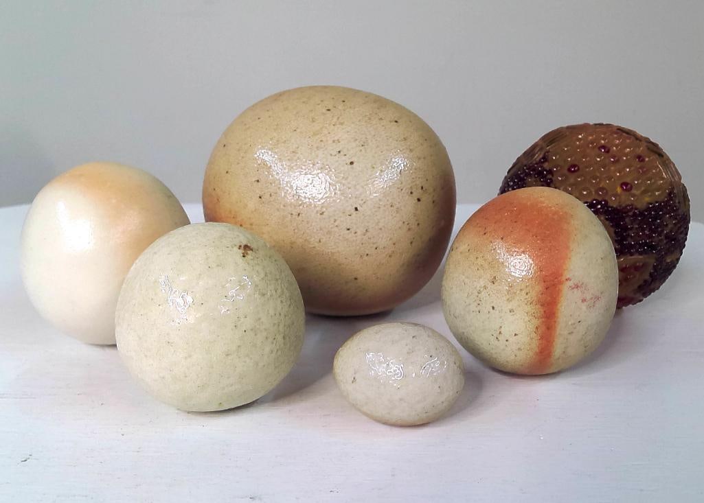 Group of Six Decorative Pottery and Art Glass Eggs: Collection comprising five ceramic decorative eggs of varying sizes and glazes together with one amber art glass egg-form sculpture featuring applied bead decoration. Unsigned. Dimensions: H 4.5 x W 5