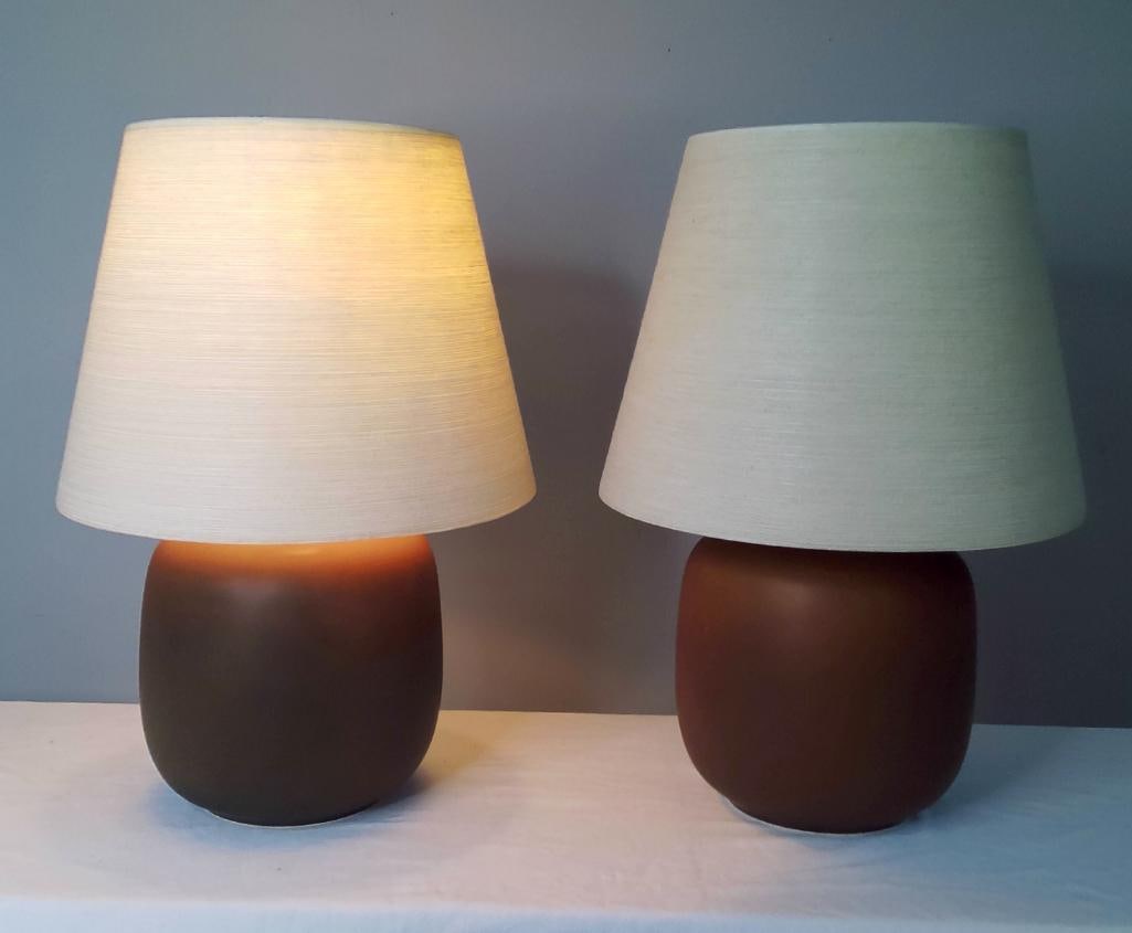 Pair of Lotte Bostlund Danish Modern Ceramic Table Lamps: Mid-century Danish Modern ceramic table lamps by Lotte Bostlund, each featuring a matte brown glazed ovoid-form body with brass-finished hardware and linen-style shades. Sold as a matched pair. Electr