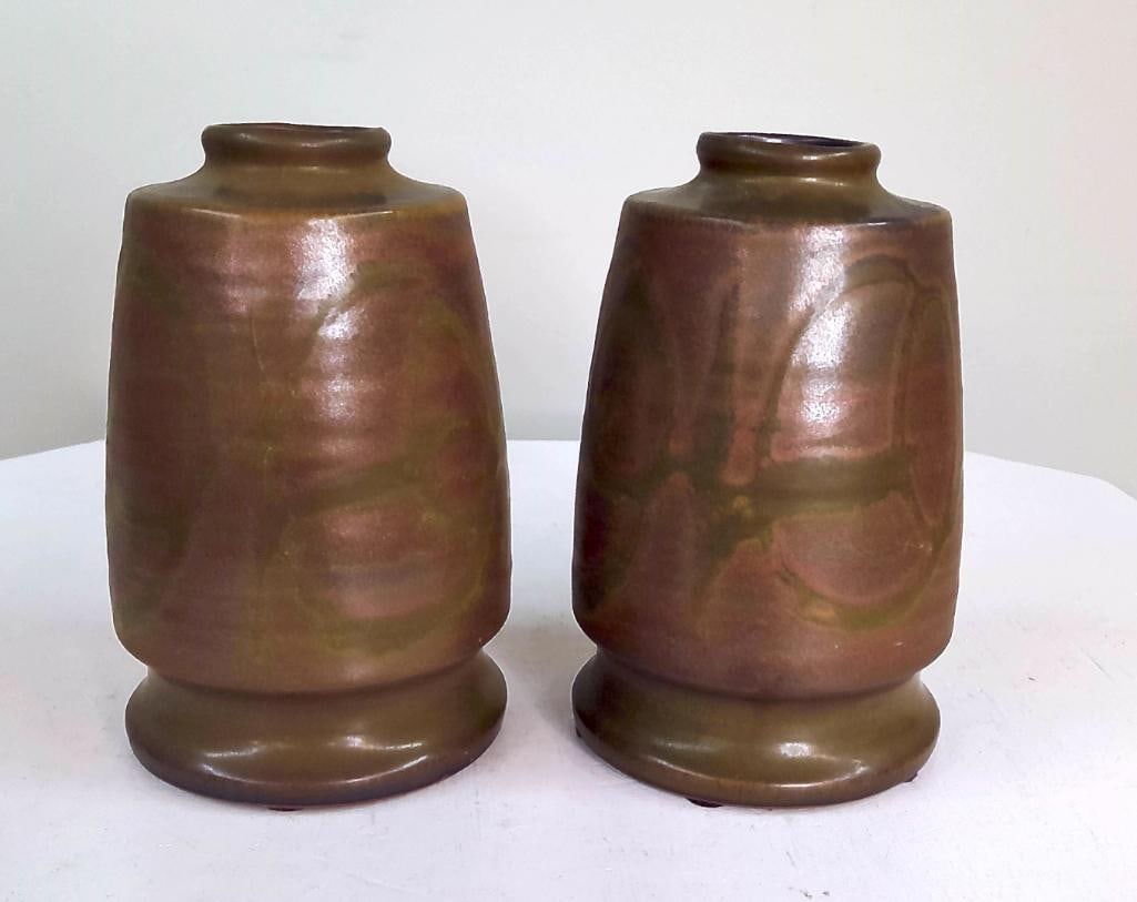 Pair of American Art Pottery Vases: A matched pair of American art pottery vases of cylindrical form with broad shoulders and flared foot rings. Finished in a mottled copper and olive-toned glaze with subtle metallic sheen. Impressed