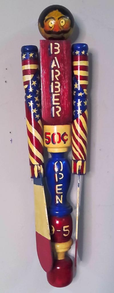 Brent Collinsworth (American/Kentucky, b. 1943): Barber, 2007, Painted and assembled wood wall sculpture depicting a mustachioed barber in patriotic red, yellow, and blue. The figure incorporates turned wooden elements, American flag motifs, applied