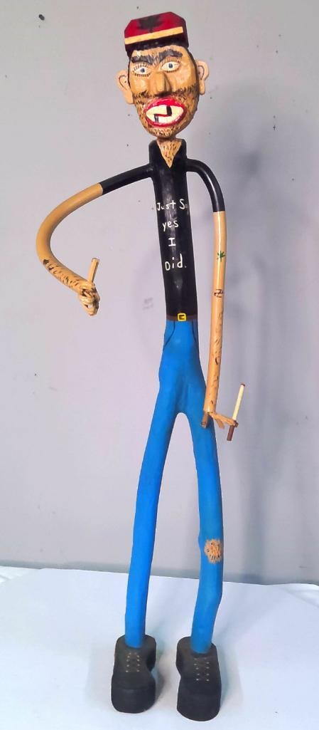 Ruthie Cooper (Kentucky, 20th Century): Just Say Yes, I Did,, Large carved, assembled, and polychrome-painted wooden folk-art figure of a man wearing a red cap decorated with a marijuana leaf. The exaggerated figure has articulated curved a