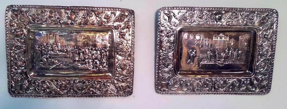 Pair of Spanish Silvered-Metal Repoussé Christopher Columbus Plaques: A pair of Spanish silvered-metal plaques worked in repoussé and chased relief, depicting episodes from the life of Christopher Columbus. The first, inscribed “Colón ante los Reyes Católicos a su 