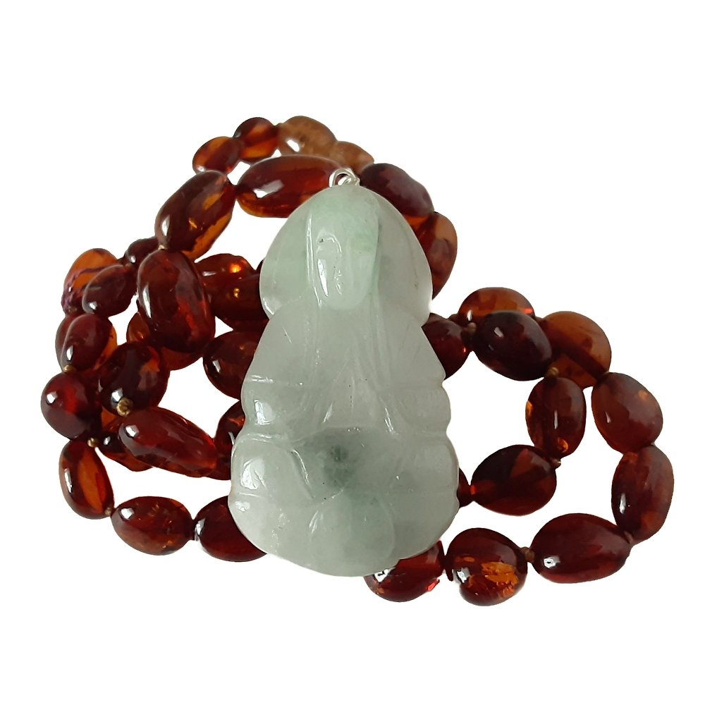 CHINESE AMBER NECKLACE WITH A QUANYIN JADEITE PENDANT: A NATURAL CHINESE AMBER NECKLACE WITH A QUANYIN JADEITE PENDANT. The oval amber beads are graduated.Necklace L: 19”, 48 cm; 27.8 g.Pendant L: 1.6”, 4 cm; W: 0.9”, 2.2 cm.Provenance: private Flor