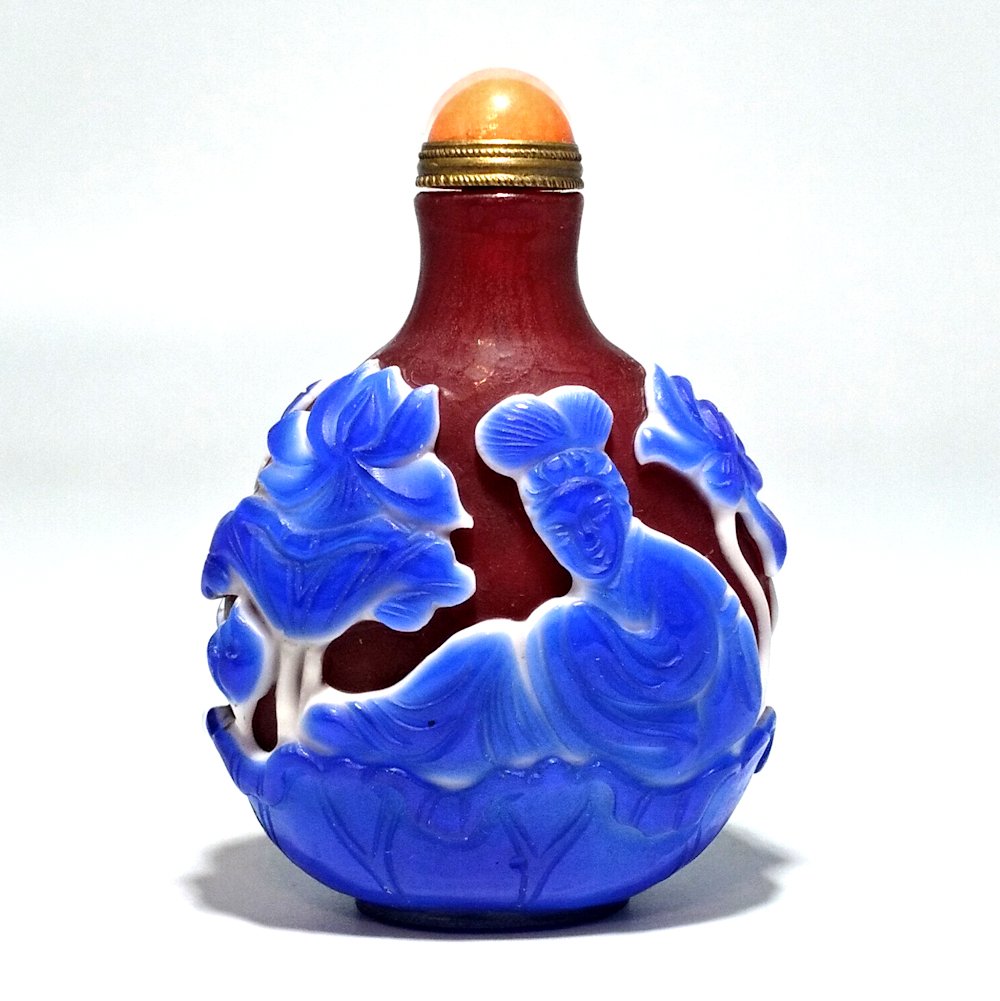 RARE PEKING GLASS SNUFF BOTTLE GUANYIN LOTUS: THE RARE AND EXQUISITE BOTTLE CARVED IN AN UNUSUAL AND STRIKING COLOR COMBINATION. IT DEPICTS GUANYIN ON BOTH SIDES- QUAN YIN, RECLINED ATOP A LOTUS, WITH LOTUS ALL AROUND HER.THE BOTTLE IS 3 INCHES T