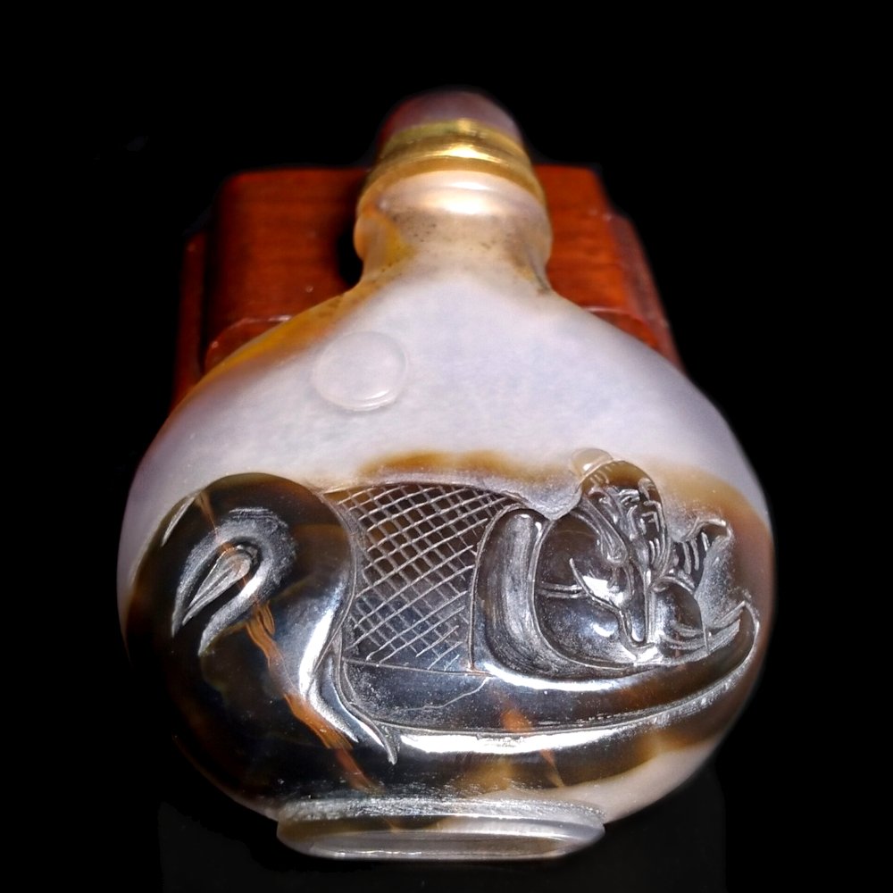 FINE MINIATURE CARVED AGATE SNUFF BOTTLE: THE BOTTLE IS WELL CARVED FEATURING AN ELDER IN A BOAT. IT HAS A WELL CARVED FOOT. THE STOPPER IS TOPPED BY A CARNELIAN CABOCHON. THE BOTTLE IS 2.15 INCHES TALL.PROVENANCE: PRIVATE FLORIDA COLLECTION.