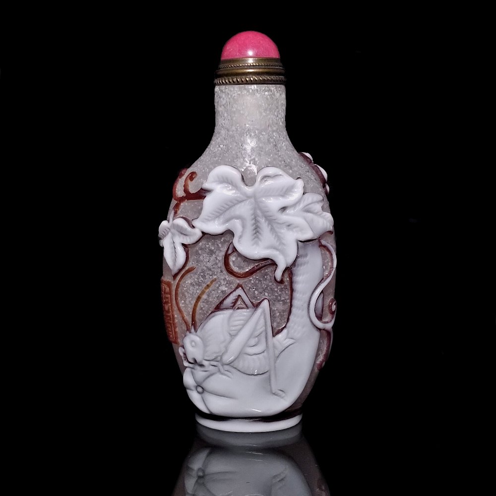 FINE PEKING GLASS SNUFF BOTTLE CRICKETS QIANLONG: THE FINE BOTTLE IS SO WELL CARVED IN THREE LAYERS OF GLASS. IT FEATURES CRICKETS, GOURDS AND LEAVES OVER BUBBLE INFUSED GLASS.IT IS SIGNED AND BEARS A QIANLONG MARK. THE BOTTLE IS 3.1 INCHES TALL. PRO
