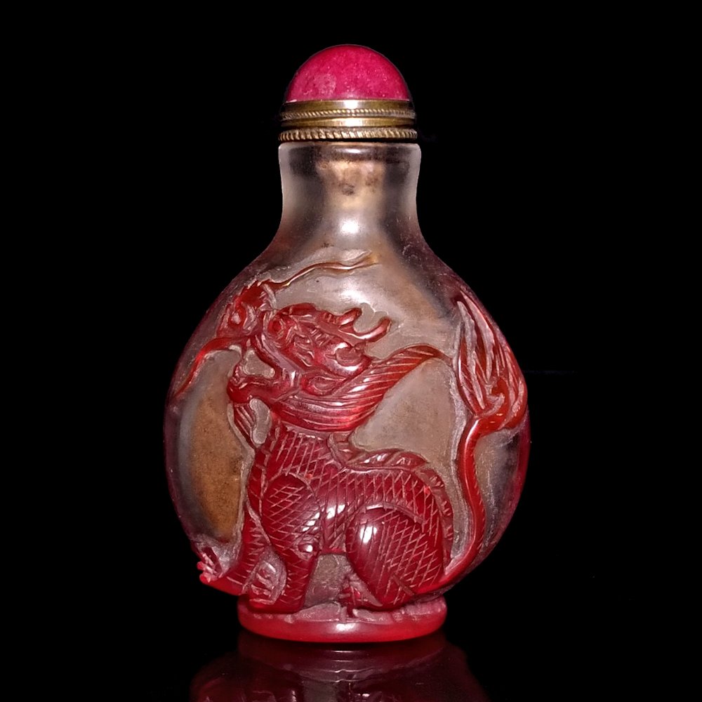 RED CHINESE PEKING GLASS SNUFF BOTTLE DRAGON PHOENIX: THE WELL CARVED BOTTLE DEPICTS A DRAGON AND A PHOENIX, CARVED IN RED GLASS OVER CLEAR. THE BOTTLE IS 3 INCHES TALL.