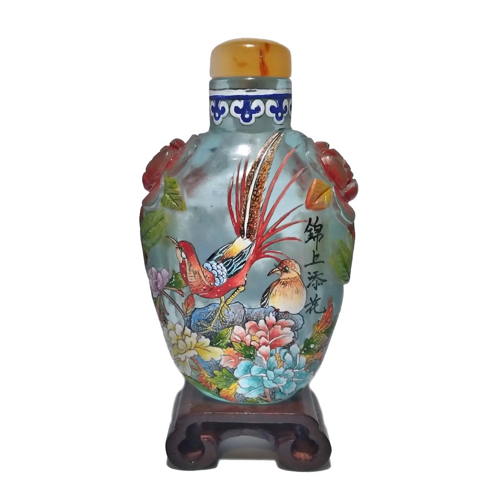 A VERY FINE SIGNED CHINESE SNUFF BOTTLE ENAMEL ON GLASS: THE STUNNING SIGNED BOTTLE IS FINELY ENAMELED OVER GLASS WITH PEONIES, OTHER FLORA AND PAESANTS. THE SHOULDERS ARE MOULDED IN THE SHAPE OF ROSES. IT BEARS A QIANLONG MARK AND AN AGATE STOPPER.IT IS 3.