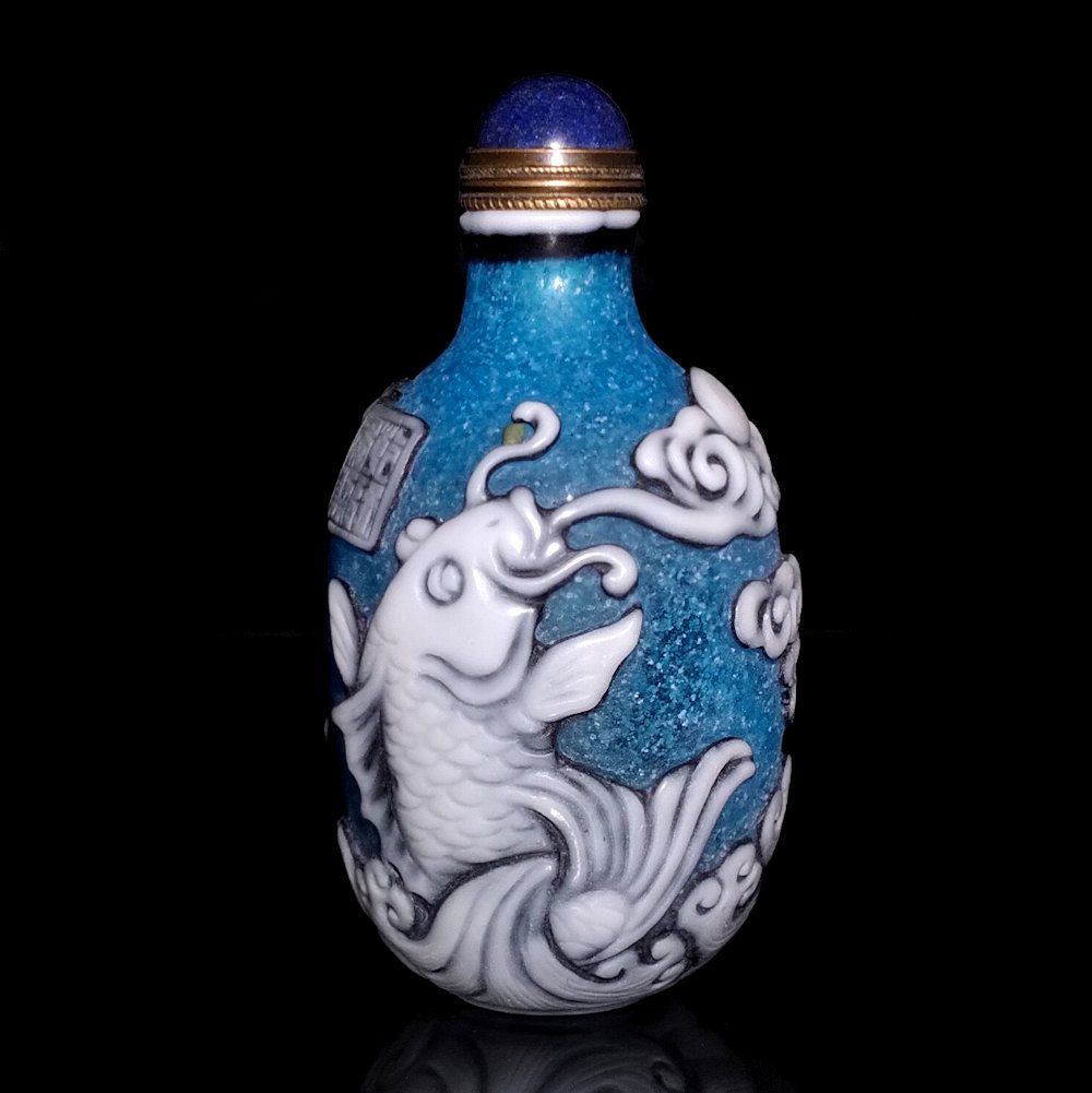 CHINESE PEKING GLASS OVERLAY SNUFF BOTTLE IMMORTAL, KOI: THE RARE BOTTLE IS CARVED IN THREE LAYERS OF COLOR. IT FEATURES AN IMMORTAL RIDING A LARGE FISH. THE BOTTLE IT 3 INCHES TALL. PROVENANCE: PRIVATE FLORIDA COLLECTION.