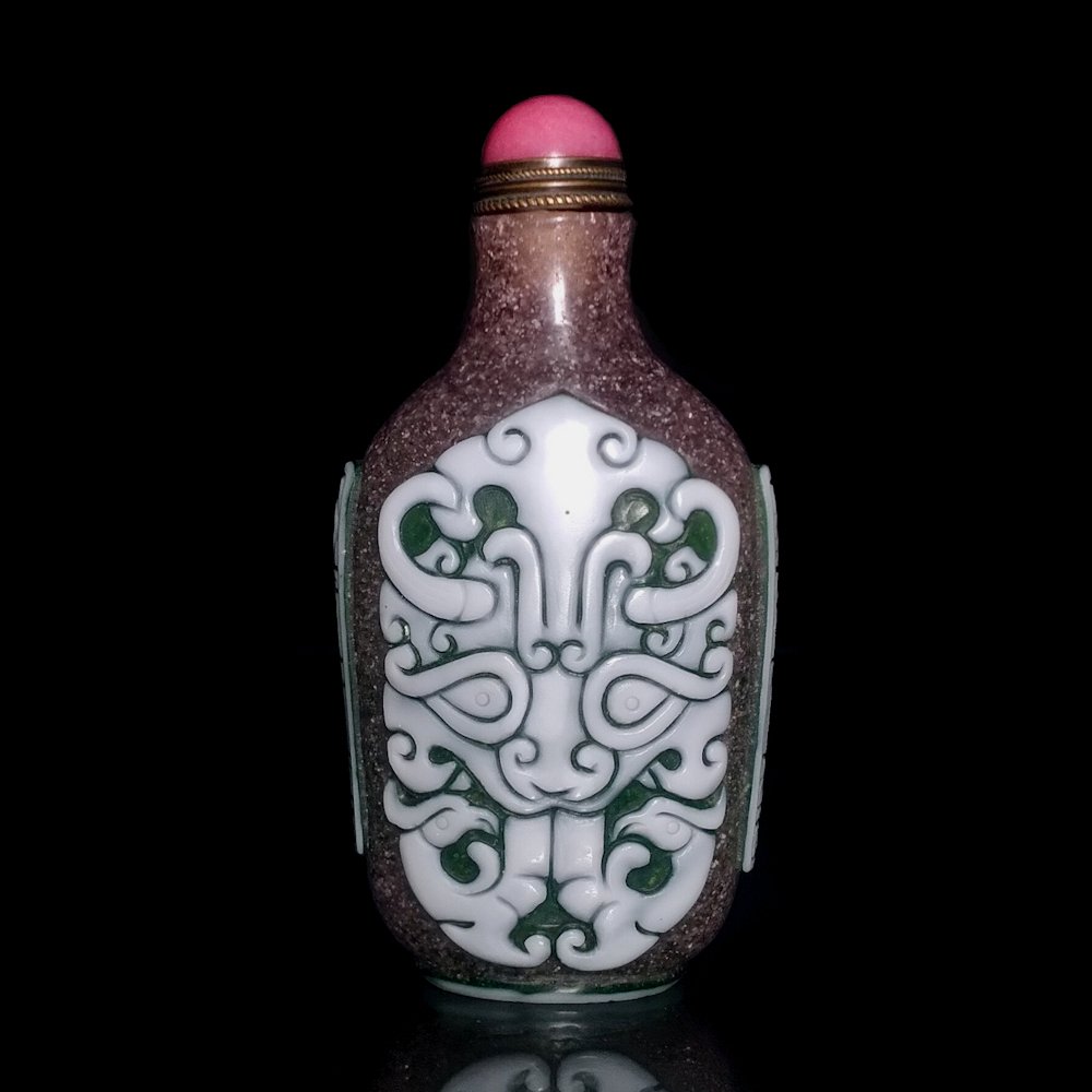 PEKING GLASS CHINESE SNUFF BOTTLE BOYS HAPPINESS: THE RARE BOTTLE IS CARVED IN THREE LAYERS OF COLOR. IT FEATURES ARCHAISTIC MASKS AND THE SHOULDERS ARE INSCRIBED WITH THE QIANLONG DATE MARK. THE BOTTLE IT 3.25 INCHES TALL. PROVENANCE: PRIVATE FLORID