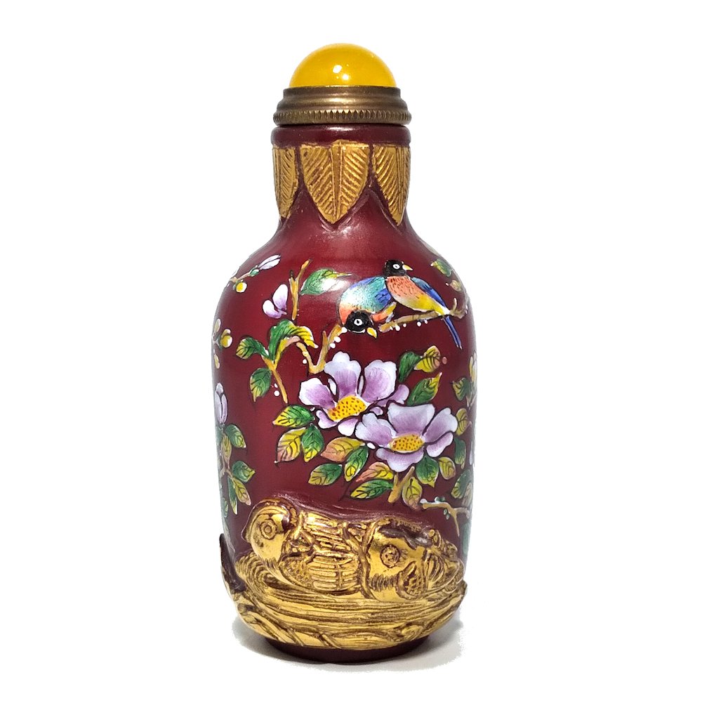 GILDED SCULPTED ENAMELED CHINESE GLASS SNUFF BOTTLE: THE EXQUISITELY ENAMELED BOTTLE IS CARVED AND GILDED AND BEARS A QIANLONG DATE MARK. DUCKS, WATER, ROCKS AND A BIRD ARE FEATURED IN HIGH RELIEF, WITH DETAILED ENAMELING ALL AROUND, ON A DEEP REDBACKGR